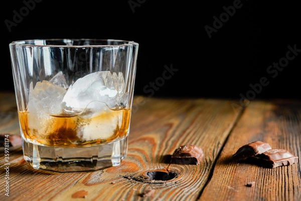Fototapeta malt scotch whiskey with ice and chocolate on wooden table