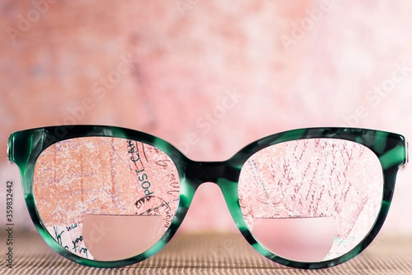 Obraz Eyeglasses Glasses with Bifocals and Black blue Frame smudged agaist written letters.  Blurry Vision Concept