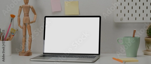 Fototapeta Artist workspace with mock-up laptop, mug, painting tools, notepad and decorations