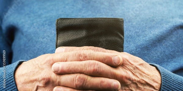 Fototapeta aged person in blue pullover hands hold small black wallet