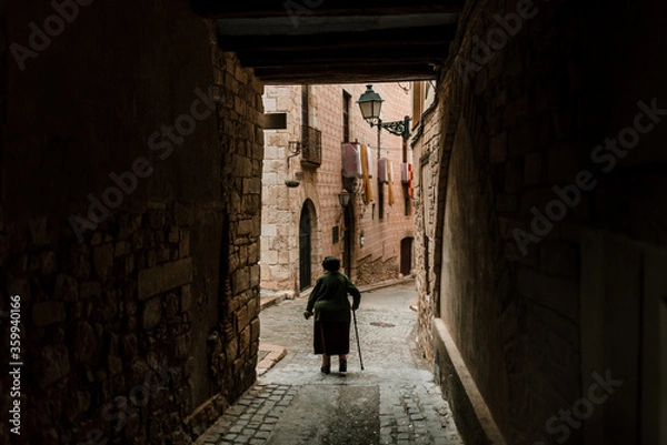 Fototapeta View of the medieval streets with and old woman walking, in Montblanc, Catalonia, Spain