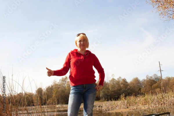 Obraz woman in red with finger up on the bank of the lake