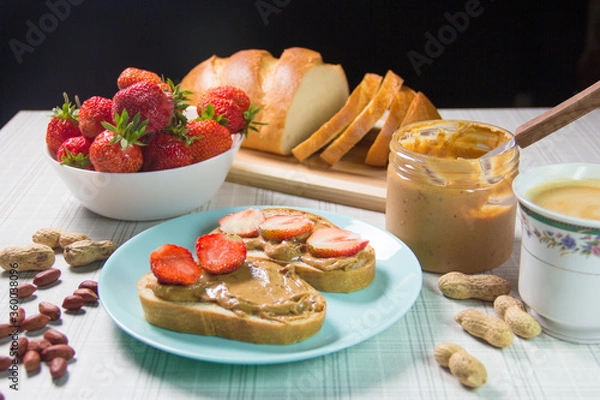 Fototapeta Breakfast with coffee and sandwiches with peanut paste and strawberries