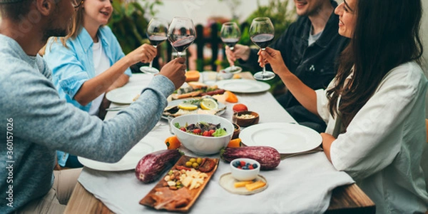 Obraz Multi ethnic Group of people dining out smiling and laughing, Friends sitting at the dinner table talking and planning to go on summer vacation together in a car with tents, Friendship Celebration