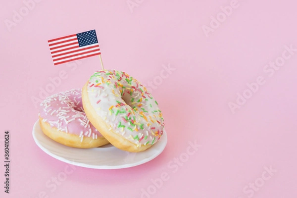 Obraz Little american flag stuck in donuts on pink background. 4th of july, usa independence day. Celebration memorial day in America. Copy space for text.