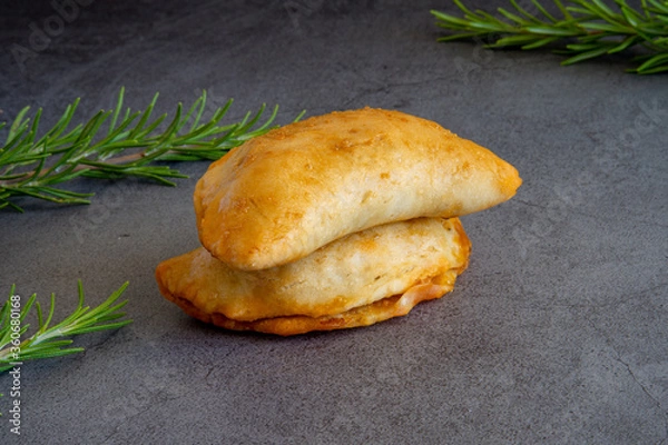 Obraz Two homemade freshly baked empanadas pastry with meat filling a gluten-free version of an authentic traditional Spanish Latin America cuisine food on a dark background 