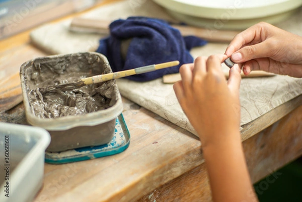 Fototapeta Motion blurred hands of girl molding the clay work with wet mud in plastic tray
