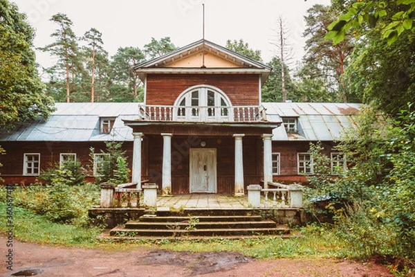 Fototapeta An old wooden noble house with a porch and a balcony in the forest. The architecture of the estate of the nineteenth century in the style of classicism