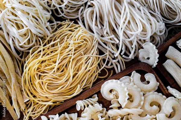 Obraz Varieties of dry pasta on a wooden plate