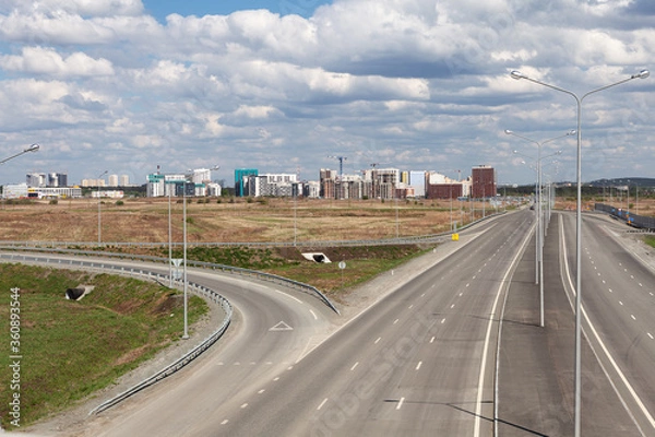Fototapeta Motorway interchange, highway, top view. On the horizon-the construction of a residential district.