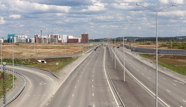 Fototapeta Motorway interchange, highway, top view. On the horizon-the construction of a residential district.