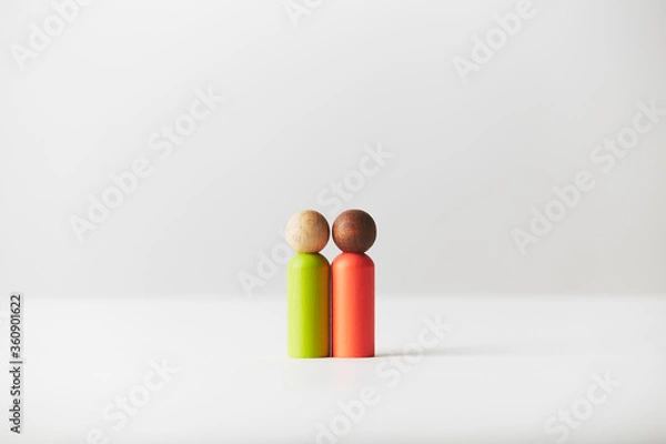 Fototapeta Wooden toy figurines concept. Mixed colour skin couple standing in the middle.   White caucasian person with black African American person. Different race couple, genders or age unknown.