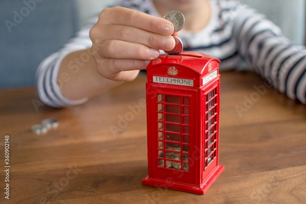 Fototapeta hand putting coin to the coin box look like traditional british call box, saving money concept