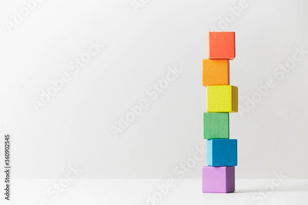 Fototapeta Wooden toys concept. Tower of wooden blocks in colours of the gay pride rainbow flag. Tower unevenly built.
