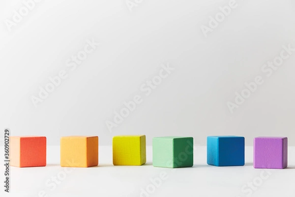 Fototapeta Wooden toys concept. Line of wooden blocks in colours of the gay pride rainbow flag. Blocks are scattered in one imperfect line