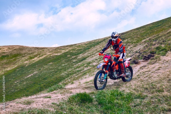 Fototapeta A beautiful landscape of the red mountain with a motorcyclist. Motocross competition.