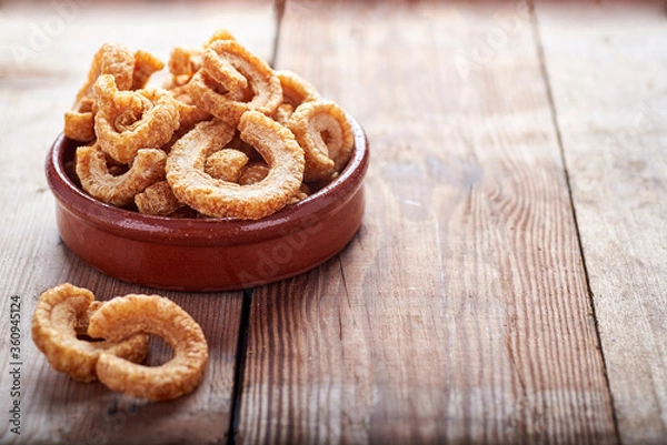 Fototapeta fried pork rinds, in a rustic container on a wooden background