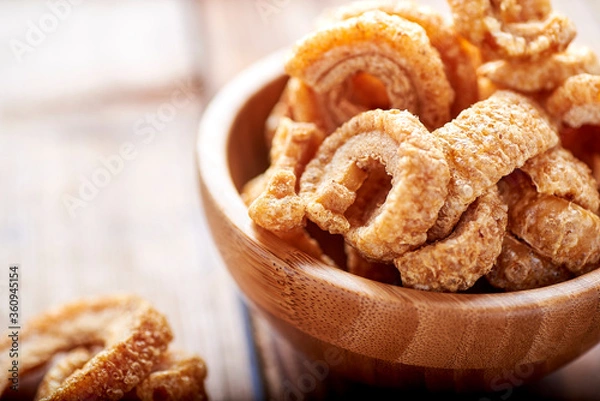 Fototapeta fried pork rinds, in a rustic container on a wooden background