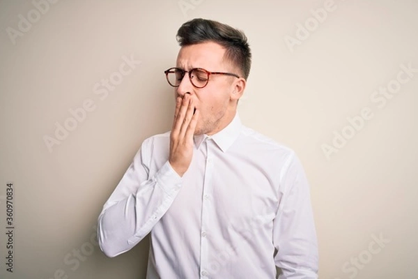 Fototapeta Young handsome business mas wearing glasses and elegant shirt over isolated background bored yawning tired covering mouth with hand. Restless and sleepiness.