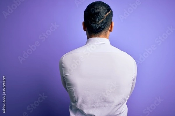 Fototapeta Young brazilian businessman wearing elegant tie standing over isolated purple background standing backwards looking away with crossed arms