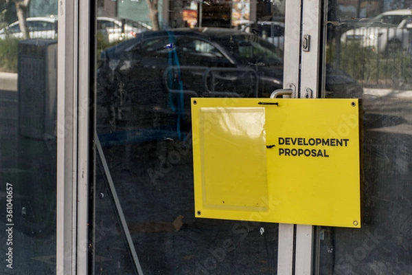 Fototapeta Development proposal yellow board on a dusty and dirty office building window in Sydney, NSW, Australia