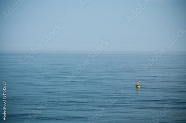 Fototapeta floating yellow signal buoy on blue sea with copy space
