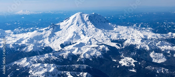 Fototapeta Aerial View of Idaho mountains from the sky while inside an airplane. View of brown mountains and trees covered with snow