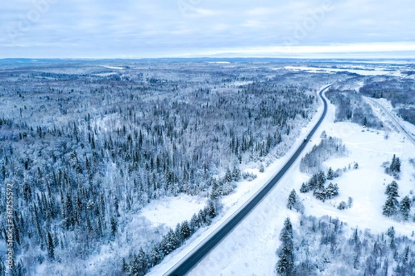 Fototapeta Aerial view on the road and forest at the winter time. Natural winter landscape from air. Forest under snow a the winter time. Landscape from drone