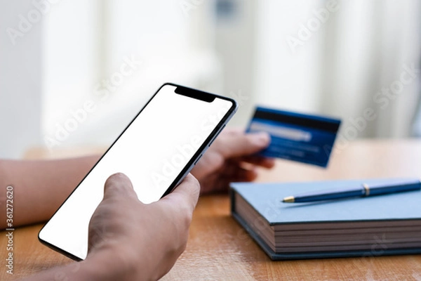 Fototapeta Mock up man hands using mobile smart phone with credit card for internet banking, online shopping and payment at home. e business concept.