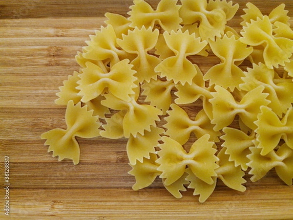 Obraz Pasta bows scattered on a wooden board.