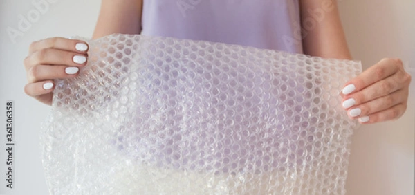 Fototapeta Cellophane film for packaging with air in female hands with copy space. Bubble Wrap Packing Close Up, Copy Space