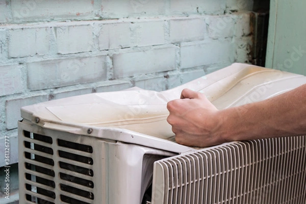 Obraz Image of angry man and broken item. .Male fist beats on the old air conditioner that crush from a strong blow. Concept of a person dissatisfied with a product or service.