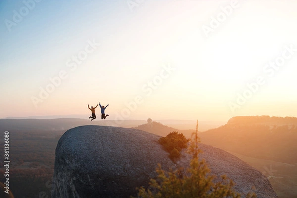 Obraz Two friends have fun and jump on top of the mountain