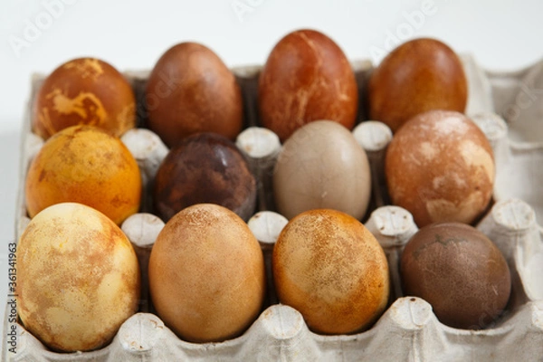 Fototapeta top front view shot of a box of twelve original, unique colorful dragon or dinosaur looking like chicken Easter eggs, dyed with natural products (red wine, tea, coffee, carrots, turmeric, soy sauce)