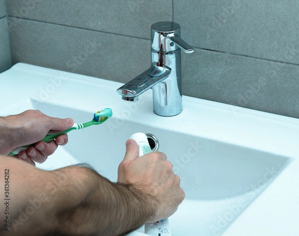 Obraz Man taking a toothbrush with a toothpaste