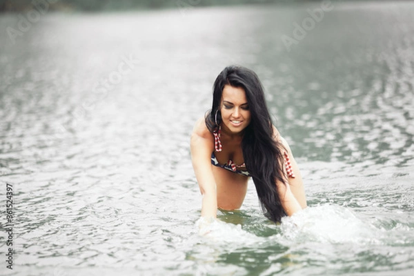 Fototapeta Woman on the beach in a swimsuit with an American flag having fun