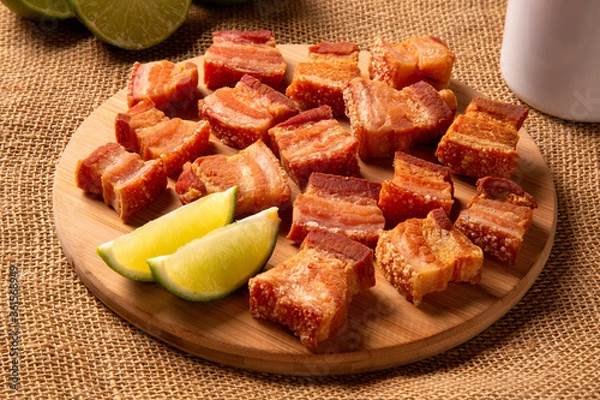 Fototapeta Deep fried crispy pork belly served with two half lemon on the table.
