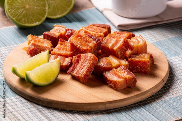 Fototapeta Deep fried crispy pork belly served with two half lemon on the table.