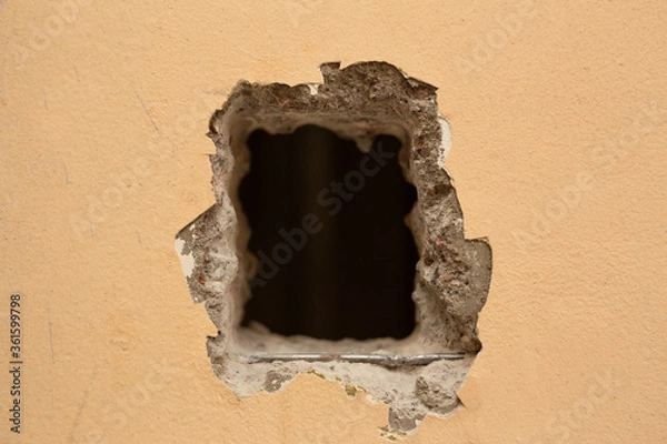 Fototapeta A hole cut in a yellow concrete wall for installing the elevator button.