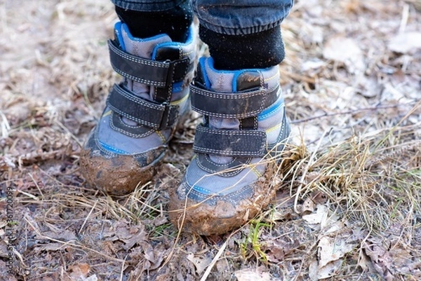 Obraz The boy went for a walk in the spring in the forest and got his shoes very dirty