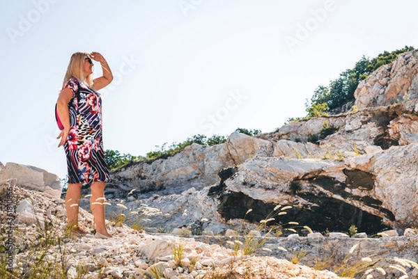 Fototapeta the woman walks alone through the mountains and observes the landscape