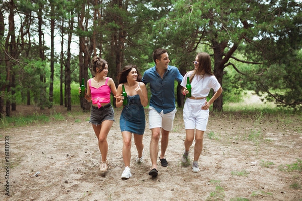 Fototapeta On the way. Group of friends walking down together during picnic in summer forest. Lifestyle, friendship, having fun, weekend and resting concept. Looks cheerful, happy, celebrating, festive.