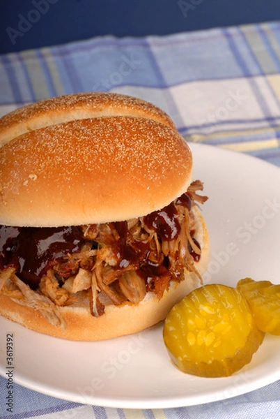 Fototapeta A pulled pork sandwich with pickles on a white plate