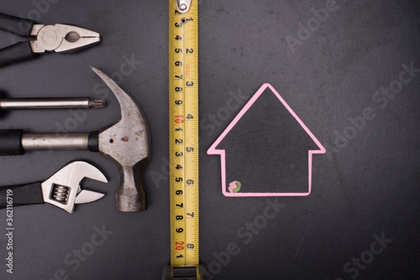 Fototapeta Set of tools with a house symbol,over wooden background