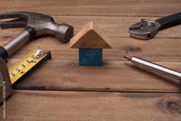 Fototapeta Set of tools with a house symbol,over wooden background