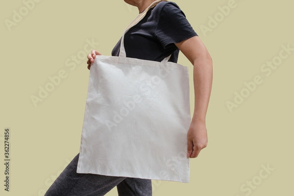 Fototapeta Woman holding reusable white cotton linen eco organic fabric tote bag isolated blank background for mockup with clipping path