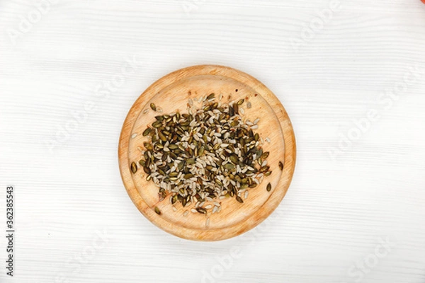 Obraz sunflower seeds end pumpkin seeds lie on a round wooden plate on a white wooden background. Organic healthy, immune natural products, top view.