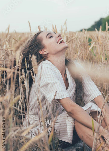 Fototapeta 
portrait of a girl of model appearance in wheat, a girl sits in a wheat field and smiles