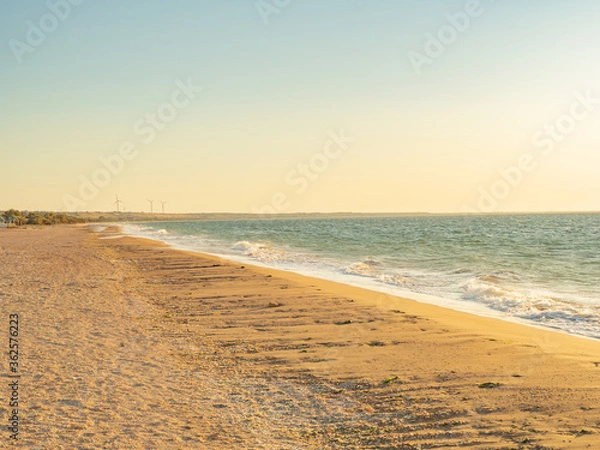 Obraz deserted beach at sunset with wind generators