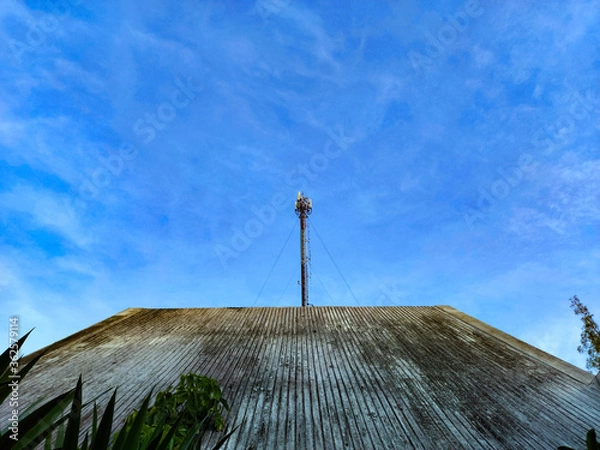Fototapeta The pole stands tall on the roof of the house. With a blue sky as a background